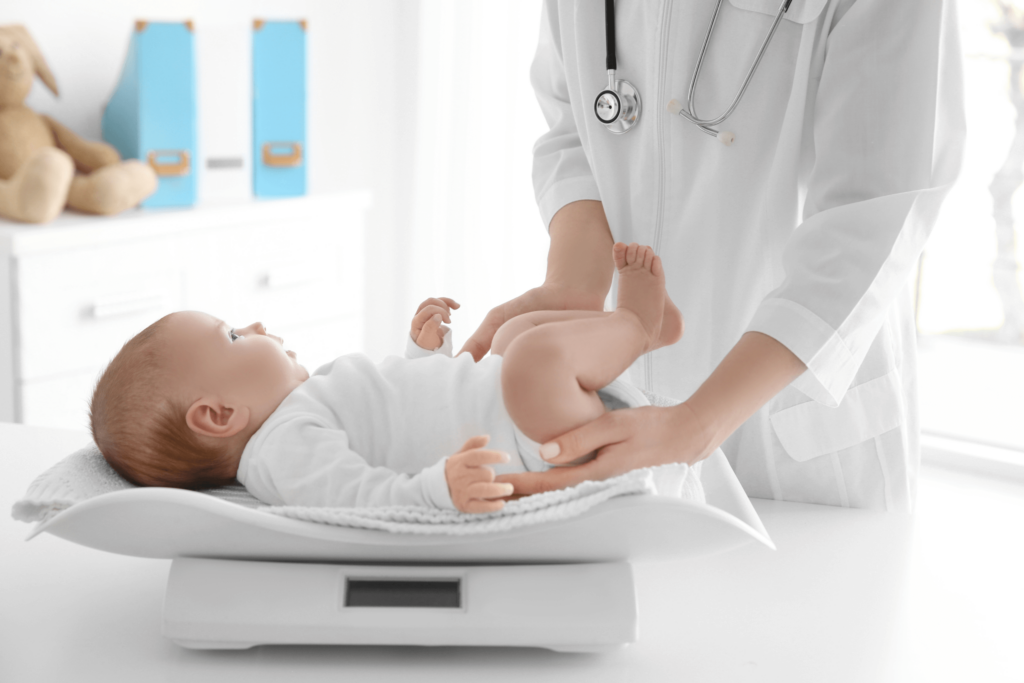 A pediatrician is measuring a baby’s weight with a scale.
